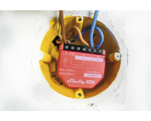 Gros plan d''un relais Shelly Gen3 dans un boîtier encastré jaune avec des câbles électriques.