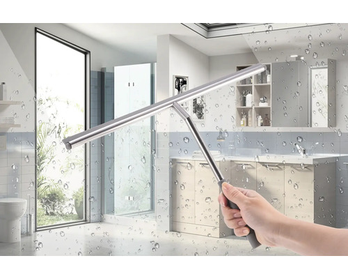 Main tenant un racloir de fenêtre pour nettoyer une cabine de douche dans la salle de bain.
