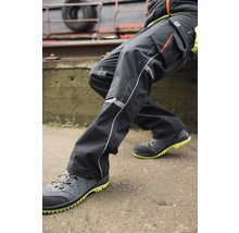 Person in Arbeitskleidung mit Arbeitshose und Sicherheitsschuhen