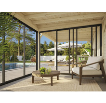 Véranda lumineuse avec mobilier de terrasse, vue sur une piscine et un jardin à travers des portes coulissantes en verre.