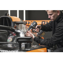 Ein Mann verwendet einen Akku-Bohrschrauber von DeWalt an einem Formel-1-Rennwagen.