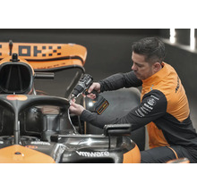 Ein Mechaniker verwendet einen Akkuschrauber, um an einem Formel-1-Rennwagen zu arbeiten.