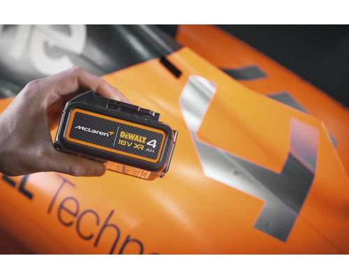 Batterie Dewalt 18 volts XR 4 Ah dans la main devant une voiture de Formule 1 McLaren.