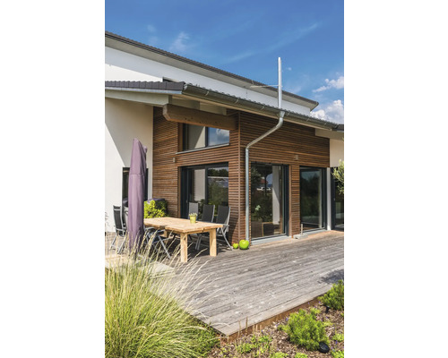 Maison moderne avec bardage en bois, terrasse et mobilier de jardin.