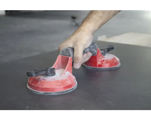 Main actionnant un élévateur à ventouses double sur un carreau