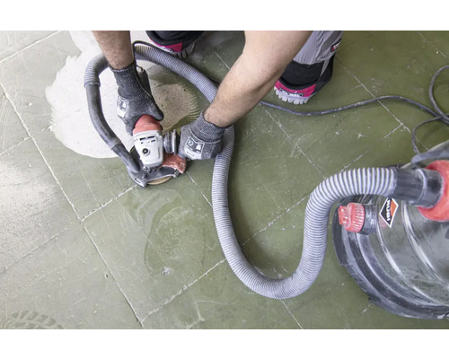 Handwerker schleift Fliesen mit einem Schleifgerät mit Staubabsaugung.
