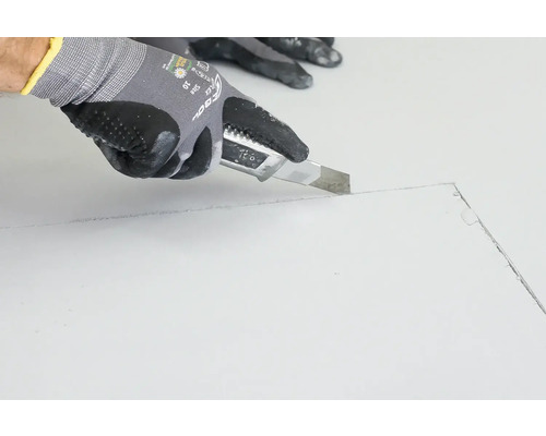 Une personne coupe une plaque avec un cutter.