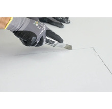 Eine Person schneidet mit einem Teppichmesser eine Linie auf einer Oberfläche.