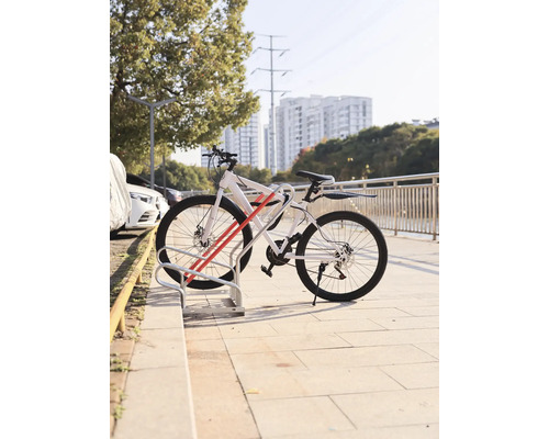 Ein weisses Fahrrad steht in einem Fahrradständer.