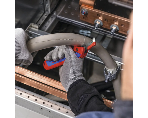 Eine Person mit Arbeitshandschuhen schneidet ein Rohr mit einem Rohrabschneider.