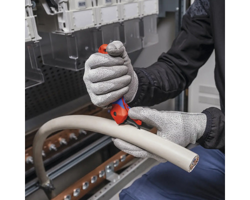 Eine Person schneidet mit einem Kabelmesser ein Kabel.