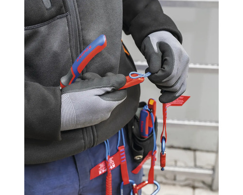 Une personne utilise une pince coupante avec une longe de sécurité.