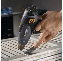 Une personne enlève de la vieille peinture avec un pistolet thermique Steinel et un couteau à mastic.