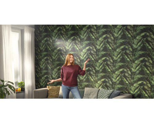 Salon avec une femme devant un papier peint à feuilles vertes