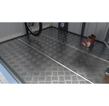 Metallboden mit Riffelblechmuster in einem Schuppen, mit Fahrrad, Stiefeln und Regalen