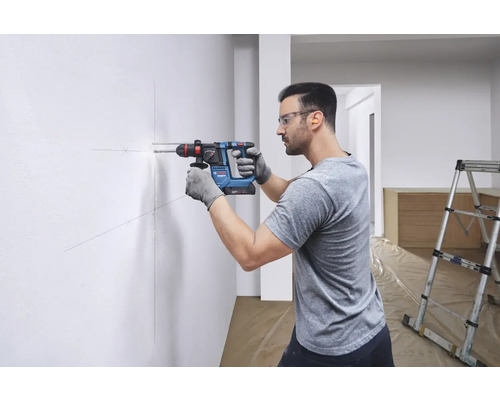 Mann bohrt mit einem Bohrhammer ein Loch in eine Wand