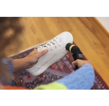 Eine Person reinigt einen Stoffschuh mit einem Dampfreiniger