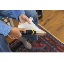 Person reinigt einen weissen Turnschuh mit einem Reinigungsgerät.