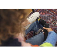 Person reinigt weisse Stoffschuhe mit einem Dampfreiniger