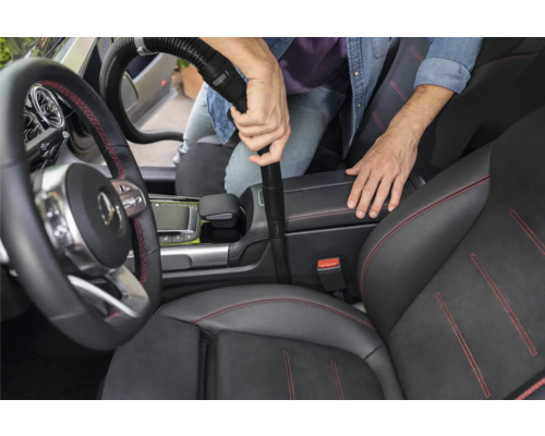 Person saugt das Innere eines Autos mit einem Staubsauger
