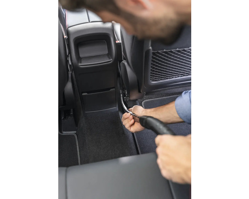 Eine Person reinigt den Innenraum eines Autos mit einem Staubsauger.