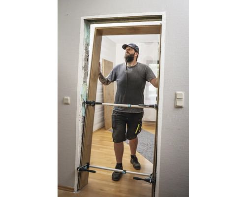 Ein Mann montiert eine Tür mit einem Türspreizer.