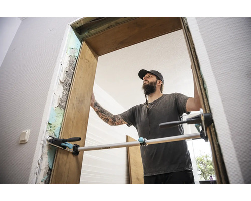 Handwerker montiert eine Holztürzarge mit einer Richtlatte