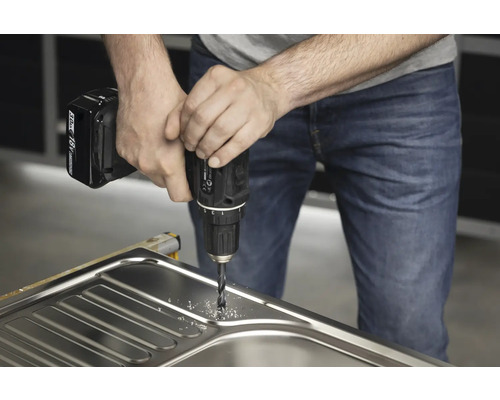 Un homme perce un évier avec une perceuse sans fil