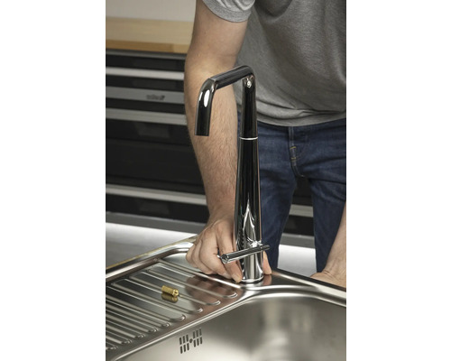 Installation d''un robinet de cuisine chromé sur un évier en acier inoxydable.