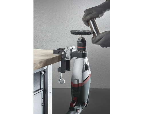 Eine an einer Werkbank befestigte Bohrmaschine mit Schleifaufsatz wird verwendet, um ein Metallstück zu bearbeiten.