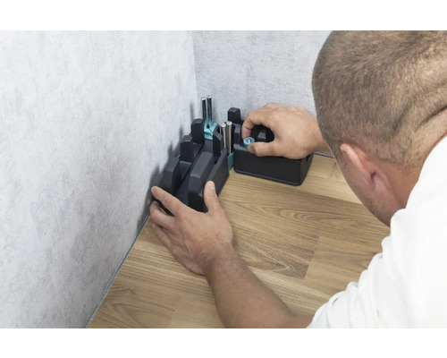 Une boîte à onglets est fixée dans un angle sur un plancher en bois.