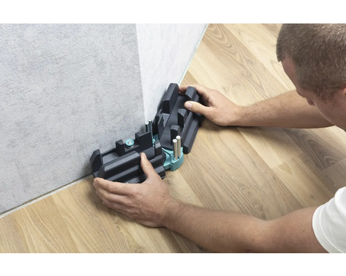 Une personne utilise une boîte à onglets pour couper des plinthes.