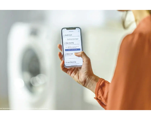 Frau hält ein Smartphone mit einer App zur Wartung eines Trockners in der Hand