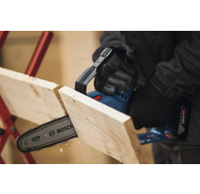 Eine Akku-Kettensäge schneidet ein Holzbrett. Bosch Logo.