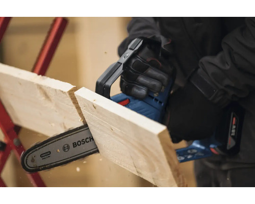 Eine Akku-Kettensäge schneidet ein Holzbrett. Bosch Logo.