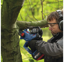 Un homme coupe une branche avec une tronçonneuse à batterie.