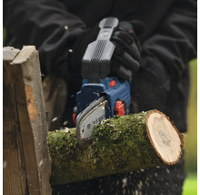 Person sägt Holzscheit mit einer Akku-Kettensäge von Bosch