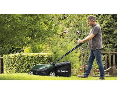 Un homme utilise une tondeuse à gazon Bosch dans un jardin.