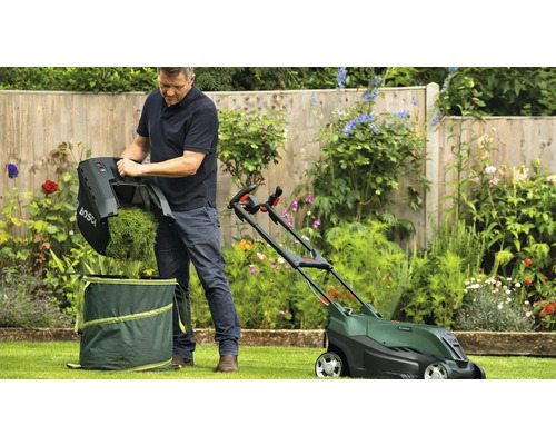 Un homme vide le bac de ramassage d''une tondeuse à gazon dans un sac de jardin