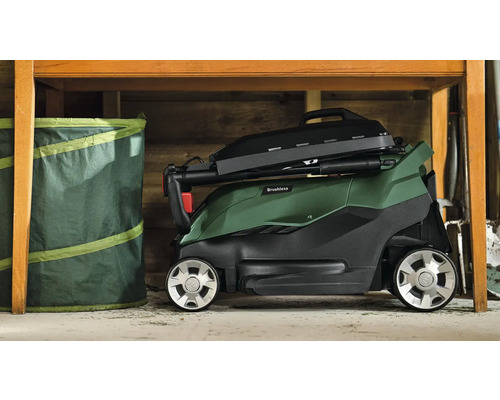 Tondeuse à gazon à batterie pliée sous une table avec un sac de jardin