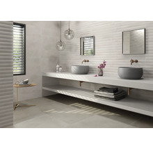 Salle de bain lumineuse avec double vasque, miroirs et carreaux muraux structurés.