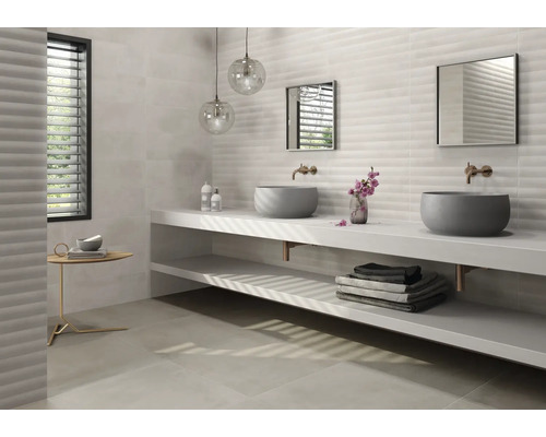 Salle de bain lumineuse avec double vasque, miroirs et carreaux muraux structurés.