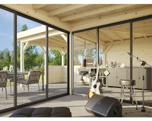 Cabane en bois claire avec de grandes baies vitrées coulissantes, espace de vie, coin cuisine et terrasse avec mobilier de jardin