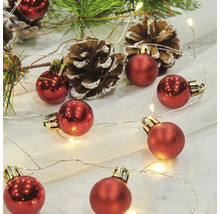 Dekorative Anordnung mit roten Weihnachtskugeln, Lichterkette, Tannenzweigen und Tannenzapfen.