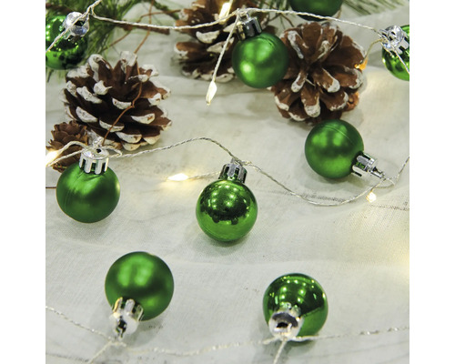 Grüne Christbaumkugeln mit Tannenzapfen und Lichterkette