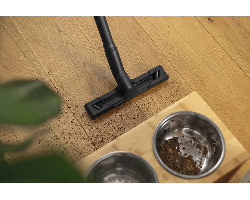 Aspirateur nettoie le sol à côté d''une gamelle pour animaux