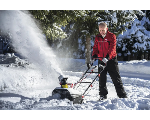 Une personne utilise une fraise à neige pour déneiger