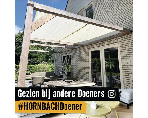 Terrasse mit Sonnensegel und Gartenmöbeln vor einem Backsteinhaus