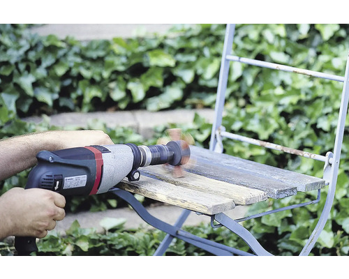 Artisan ponçant une chaise en bois avec une perceuse et un embout de ponçage à l''extérieur.