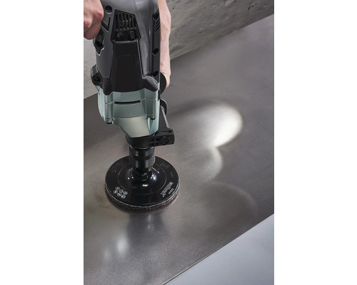 Une ponceuse avec disque de ponçage est utilisée sur une surface métallique.